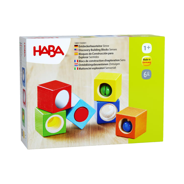 Abgebildet ist eine Schachtel mit HABA Discovery Building Blocks Senses für Kinder ab 1 Jahr. Die Schachtel zeigt vier bunte Bausteine mit sensorischen Elementen und Text in mehreren Sprachen sowie das HABA-Logo und das Label "Made in Germany".