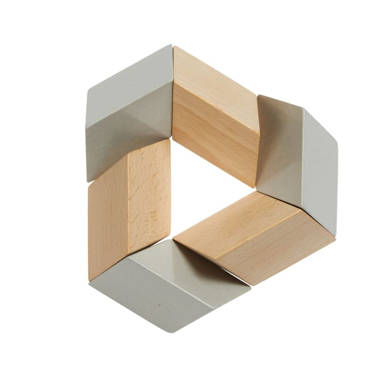 Vier rechteckige Holzklötze mit grauen Enden sind so angeordnet, dass sie eine offene, eckige Schleife bilden, die an ein unvollständiges Quadrat oder eine geometrische Form auf weißem Grund erinnert.