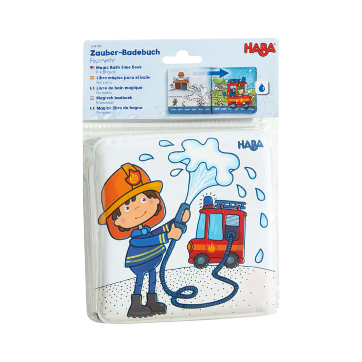 Ein verpacktes HABA Magic Bath Time Book zeigt ein Kind im Feuerwehr-Outfit, das neben einem roten Feuerwehrauto mit einem Schlauch Wasser versprüht. Die Verpackung enthält Produktinformationen in mehreren Sprachen.