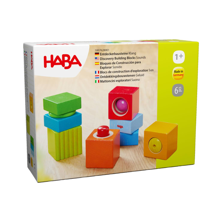 Eine Schachtel mit HABA Discovery Building Blocks Sounds für Kinder ab 1 Jahr. Die Schachtel zeigt bunte Holzklötze, einige mit Fenstern oder Knöpfen, und enthält Produktinformationen in mehreren Sprachen.