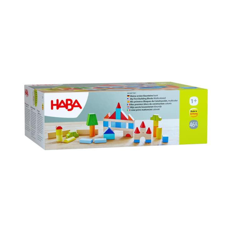 Eine rechteckige Schachtel mit HABA-Bauklötzen, die ein Bild mit bunten geometrischen Holzklötzen zeigt, die in verschiedenen Strukturen angeordnet sind. Auf der Schachtel steht, dass sie für Kinder ab 1 Jahr geeignet ist und 46 Teile enthält.