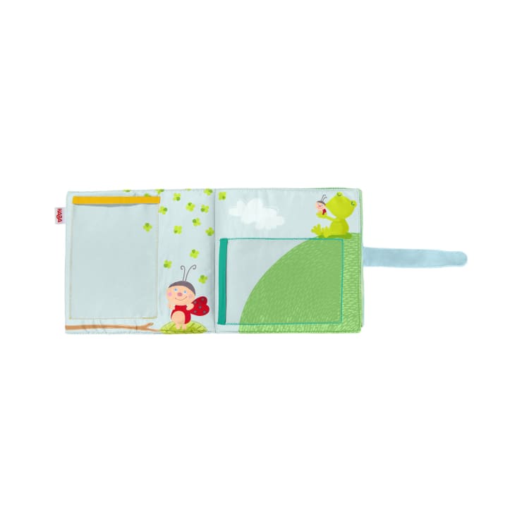 Ein rechteckiger Organizer aus Stoff mit Taschen, mit Abbildungen eines Marienkäfers, eines Froschs, eines grünen Hügels, von Kleeblättern und einer Wolke auf hellblauem Hintergrund und einem blauen Stoffband auf der rechten Seite.