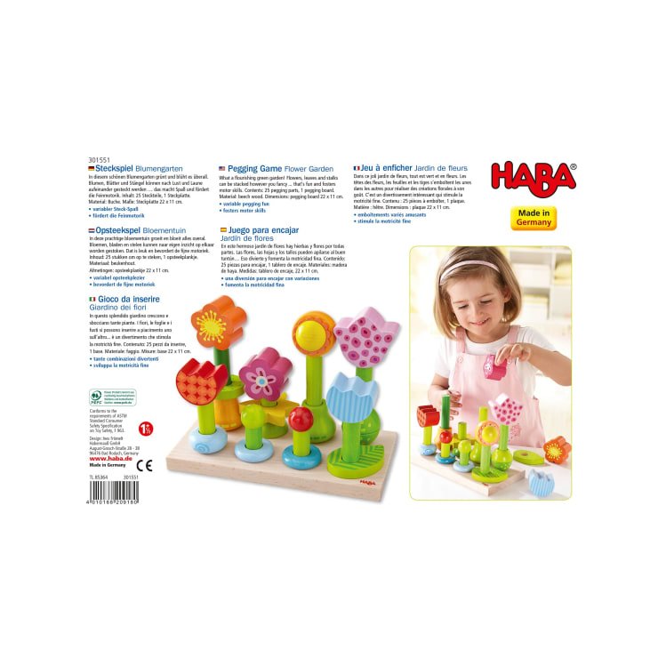 Eine HABA-Spielzeugschachtel zeigt bunte Holzblumen, die auf Wäscheklammern zusammengesetzt werden können, mit Produktinformationen in mehreren Sprachen. Ein junges Mädchen auf der rechten Seite spielt mit dem zusammengebauten Spielzeug.