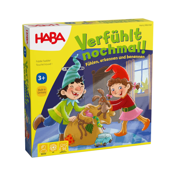 Die Abbildung zeigt die gelbe Schachtel des Brettspiels Verfühlt nochmal! von HABA. Die Illustration zeigt zwei Kinder mit Elfenmützen, die lächelnd in einem gemütlichen, sonnendurchfluteten Raum Spielzeug aus einem braunen Sack ziehen.
