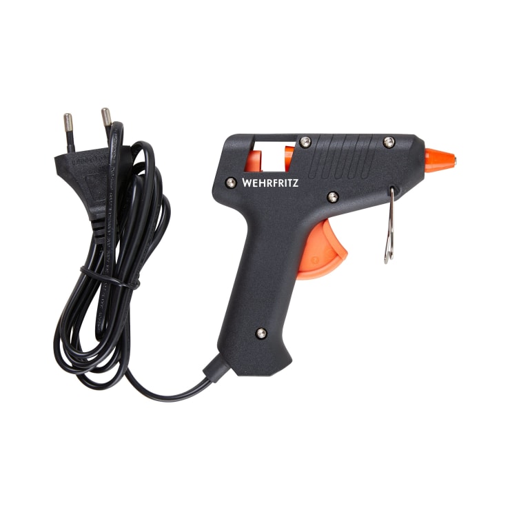 Eine schwarze elektrische Heißklebepistole mit der Aufschrift HABA Pro, mit angeschlossenem Netzkabel und Stecker, mit orangefarbenem Abzug und Düse, fotografiert auf weißem Hintergrund.