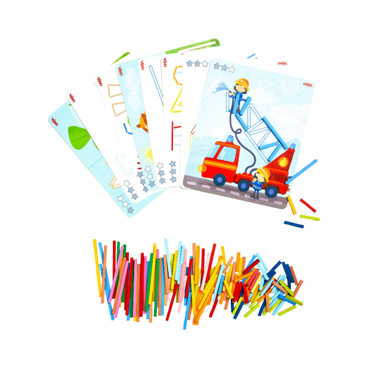 Mehrere illustrierte Aktivitätskarten sind über einem Stapel bunter Plastik- oder Holzstäbchen ausgebreitet, wahrscheinlich für ein Lern- oder Zuordnungsspiel für Kinder. Die Karten enthalten Bilder und geometrische Formen.