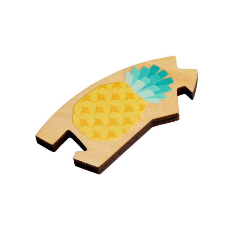 Ein hölzernes Puzzleteil mit einer Illustration einer gelben Ananas mit grünen Blättern, isoliert auf einem weißen Hintergrund.