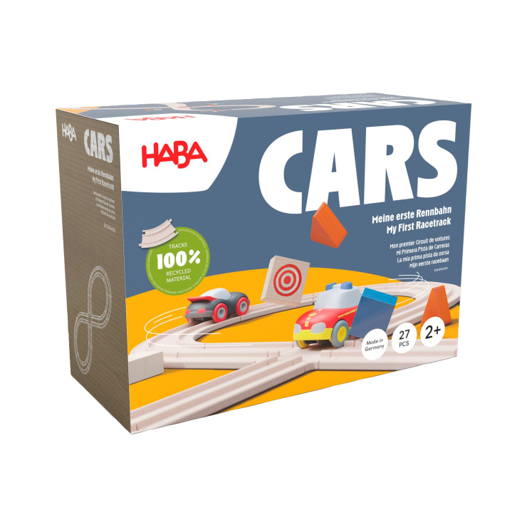 Eine Schachtel mit dem HABA-Spielzeugset My First Racetrack, das Bilder von Holzschienen, zwei Spielzeugautos und Hindernissen zeigt. Auf der Schachtel steht, dass es 27 Teile enthält und für Kinder ab 2 Jahren geeignet ist.