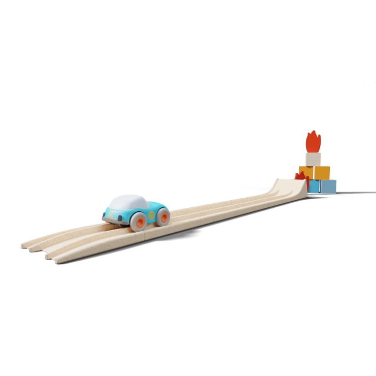 Ein blaues Spielzeugauto mit orangefarbenen Rädern rollt eine hölzerne Rampe hinunter zu einem kleinen Stapel bunter Blöcke, die mit roten Flammenformen versehen sind. Der Hintergrund ist einfarbig weiß.