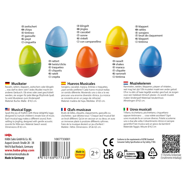 Fünf bunte, eiförmige Musikspielzeuge sind in den Farben Blau, Grün, Gelb, Orange und Rot abgebildet und jeweils in mehreren Sprachen beschriftet. Die Verpackung enthält Produktdetails, Sicherheitssymbole und Unternehmensinformationen.