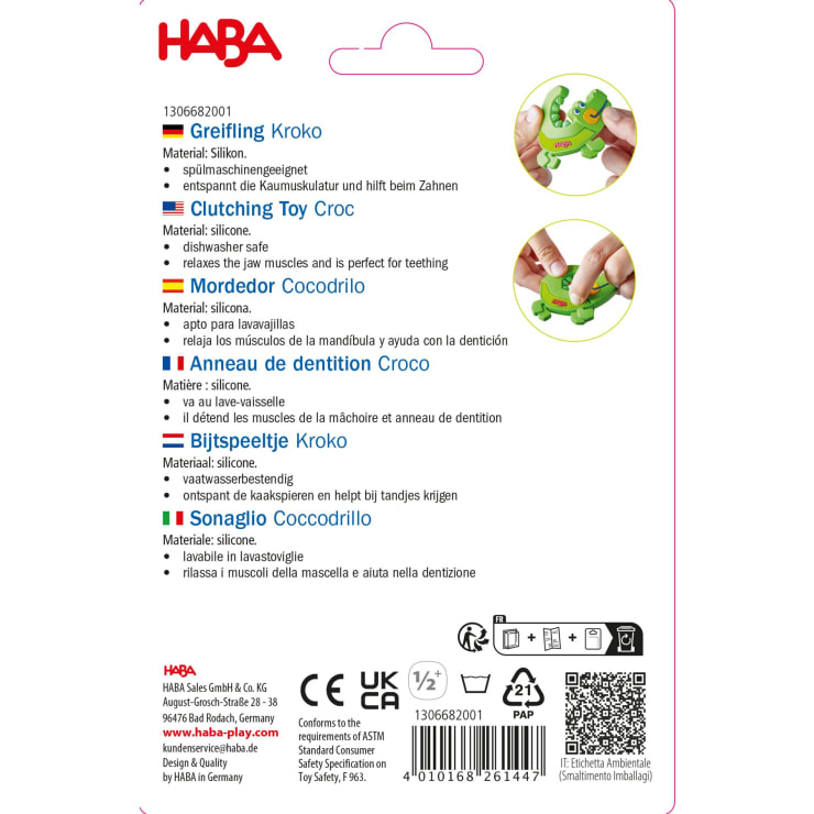 Produktverpackung für ein HABA-Beißspielzeug "Clutching Toy Croc" aus Silikon, mit mehrsprachigen Beschreibungen und Symbolen für Sicherheits- und Materialinformationen auf weißem Hintergrund mit roten Akzenten.