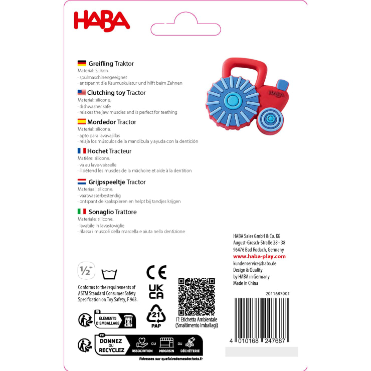 Produktverpackung für ein HABA Greifling Traktor-Beißspielzeug. Der Text beschreibt das Material (Silikon), die Vorteile beim Zahnen und bietet Übersetzungen in mehreren Sprachen. Symbole und Unternehmensangaben erscheinen am unteren Rand.
