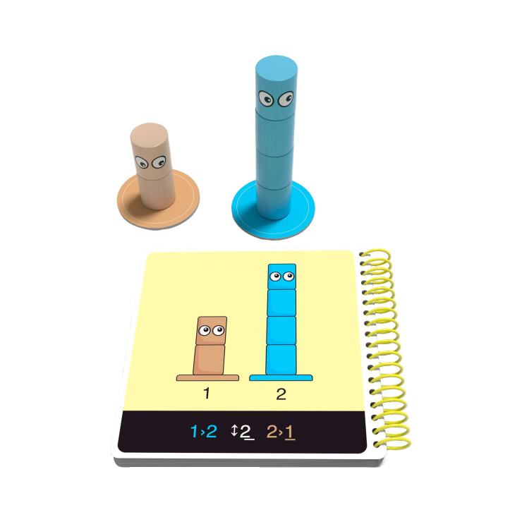 Ein Spielzeugset für den Mathematikunterricht mit zwei Stapeln farbiger Zylinder, einem braunen und einem blauen, jeweils mit Augen, neben einem aufgeschlagenen Heft mit passenden Abbildungen und Zahlen für jeden Stapel.