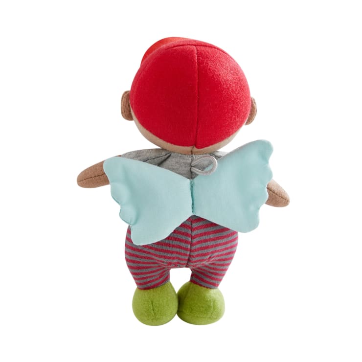 Eine Plüschpuppe, von hinten gesehen, mit einem roten Hut, blauen Stoffflügeln, einem grauen Hemd, einer rot und lila gestreiften Hose und grünen Schuhen. Die Arme der Puppe sind ausgestreckt.