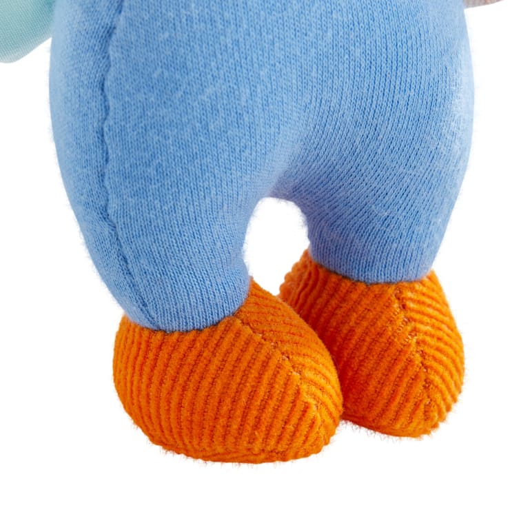 Nahaufnahme eines Plüschtiers, das eine blaue Stoffhose und orangefarbene, strukturierte Schuhe trägt, von der Taille abwärts vor einem weißen Hintergrund.