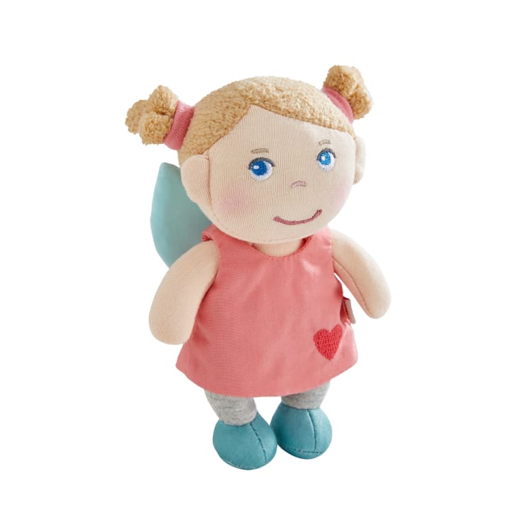Eine weiche Stoffpuppe mit hellbraunem Haar in Zöpfen, blauen Augen und einem rosa Kleid mit rotem Herz. Die Puppe hat hellblaue Flügel, graue Leggings und blaue Schuhe. Der Hintergrund ist weiß.