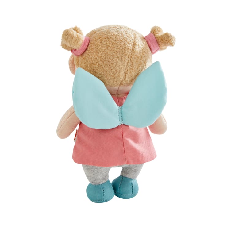Eine Plüschpuppe mit hellbraunem Haar in zwei Dutts, einem rosa Kleid, blauen Flügeln, grauen Leggings und blauen Schuhen, von hinten gesehen.
