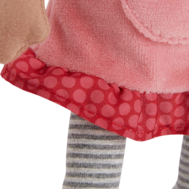 Nahaufnahme einer Puppe, die ein rosa Kleid mit roter Tupfenborte und grau-weiß gestreiften Leggings trägt. Nur ein Teil des Arms, des Kleides und der Beine der Puppe sind sichtbar.