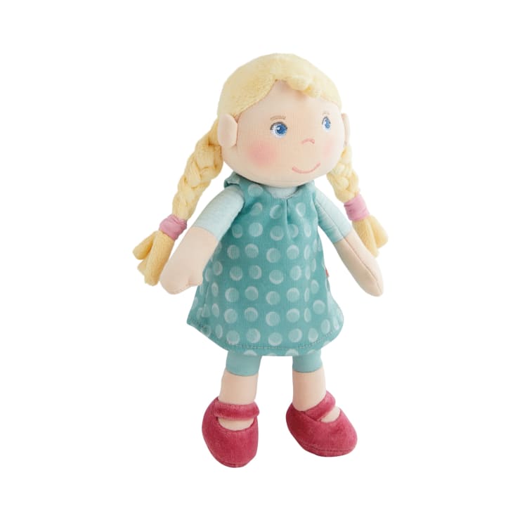 Eine weiche Stoffpuppe mit blondem Garnhaar in zwei Zöpfen, blauen Augen, einem blaugrünen Kleid mit weißen Tupfen, hellblauen Leggings und roten Schuhen, dargestellt vor einem weißen Hintergrund.
