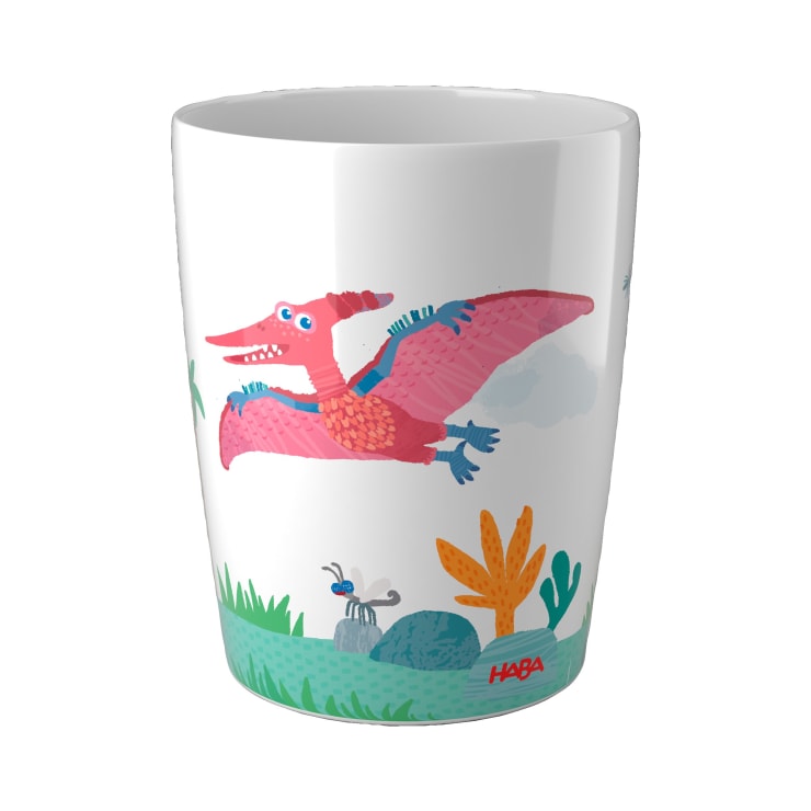 Ein weißer Becher mit einer farbenfrohen Illustration eines rosafarbenen und roten Pterodactyls, der über grüne Pflanzen, Felsen und ein Insekt fliegt, mit dem HABA-Logo in Rot am unteren Rand.