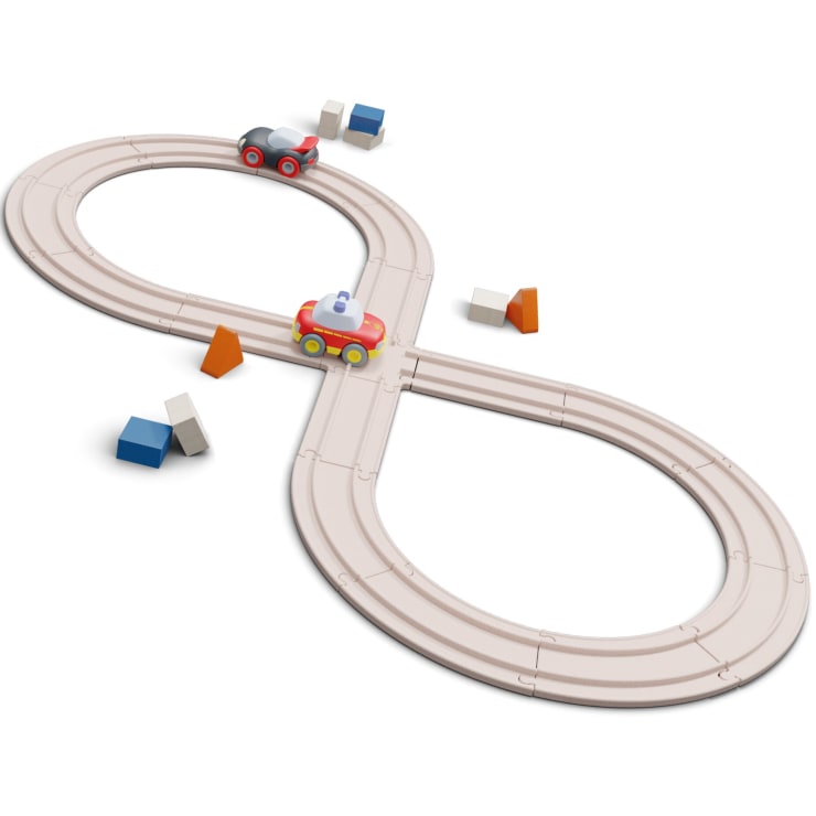 Ein hölzernes Spielzeugeisenbahngleis in Achterform mit zwei Spielzeugautos darauf. Mehrere kleine, bunte Blöcke sind in der Nähe der Strecke platziert. Der Hintergrund ist weiß.