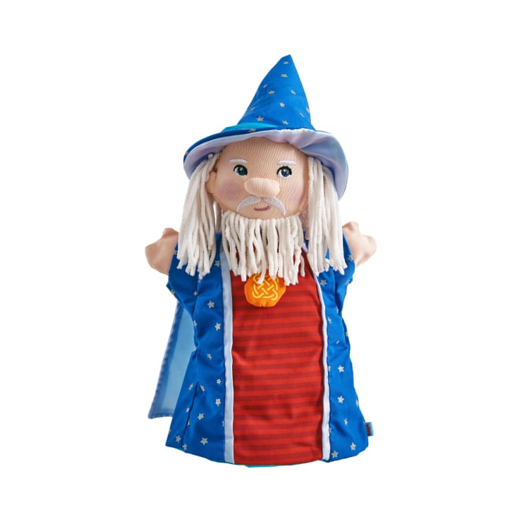 Eine Handpuppe aus Stoff in Form eines Zauberers mit blauem Hut und Gewand mit weißen Sternen, Haaren und Bart aus weißem Garn und einem roten Hemd mit einem orangefarbenen Medaillon auf weißem Hintergrund.