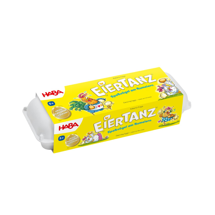 Eine rechteckige gelbe Schachtel mit der Aufschrift Eiertanz von HABA, auf der Cartoon-Hühner und Eier abgebildet sind, steht auf einem weißen Hintergrund. Die Verpackung ähnelt einem Eierkarton und weist darauf hin, dass das Spiel für Kinder ab 5 Jahren geeignet ist.