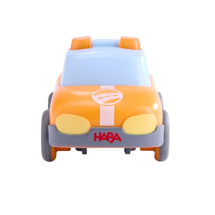Frontansicht eines kleinen orange-blauen Spielzeugautos mit gelben Scheinwerfern, grauen Rädern und der Aufschrift "HABA" auf der vorderen Stoßstange, fotografiert vor einem weißen Hintergrund.