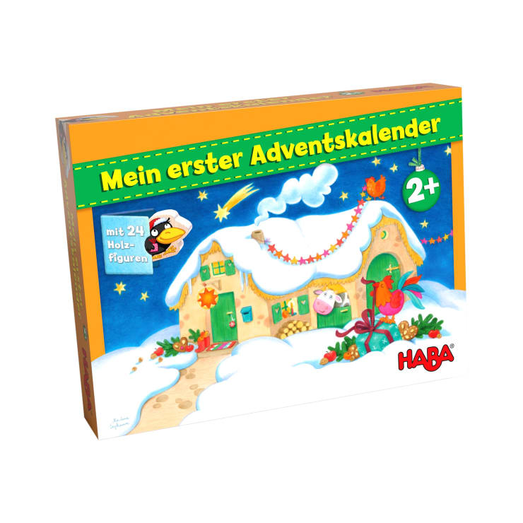 Eine Box von Mein erster Adventskalender von HABA, verziert mit einem verschneiten Haus und weihnachtlichen Details, geeignet für Kinder ab 2 Jahren, mit 24 Holzfiguren.