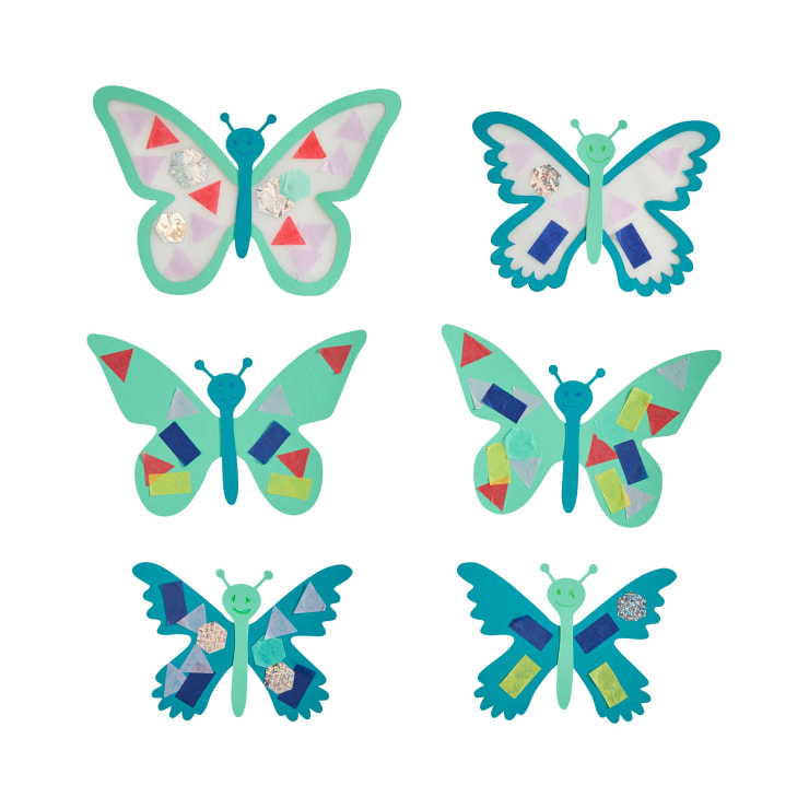 Sechs Papierschmetterlinge sind in zwei Spalten und drei Reihen angeordnet. Jeder Schmetterling ist mit Papierstücken in verschiedenen Formen und Farben verziert, wodurch einzigartige Flügelmuster entstehen. Die Hintergründe sind weiß.