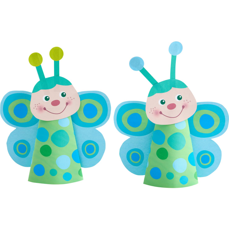 Zwei Papierbasteleien in Form von Schmetterlingen, jeweils mit lächelndem Gesicht, blauen Flügeln mit grünen und blauen Punkten und grünen kegelförmigen Körpern, die mit blauen und grünen Kreisen verziert sind.