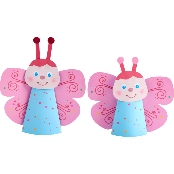 Zwei Papierbasteleien in Form von Schmetterlingen mit rosa Flügeln, blauen kegelförmigen Körpern, roten Fühlern und lächelnden Gesichtern. Die Flügel haben gewirbelte und gepunktete Muster in verschiedenen Farben.