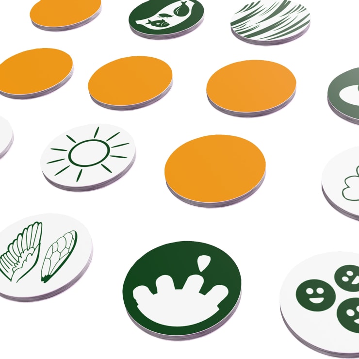 Kreisförmige Spielsteine sind in einem diagonalen Muster angeordnet. Einige Spielsteine sind einfarbig orange, während andere weiß mit einfachen grünen Illustrationen sind, darunter eine Sonne, eine Hand, lächelnde Gesichter und verschiedene Objekte. Der Hintergrund ist weiß.
