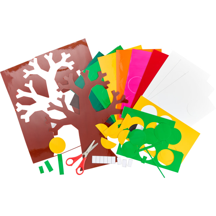 Eine Vielzahl von farbigen Papierbögen, darunter ein brauner Baumausschnitt, Kreise und Rechtecke, liegen auf einer Fläche neben einer Schere mit rotem Griff.