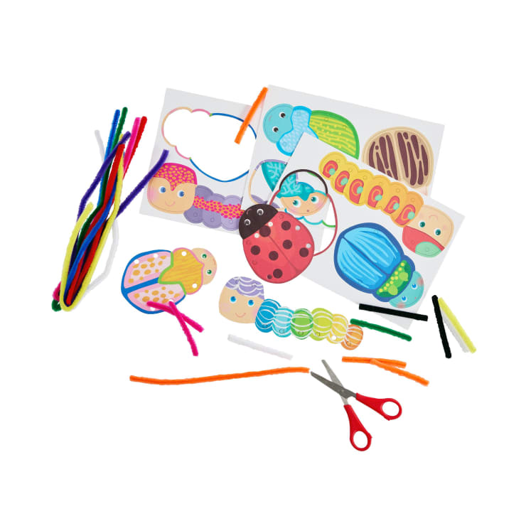 Verschiedenes Bastelmaterial, darunter farbige Pfeifenreiniger, Sicherheitsscheren und illustrierte Insektenausschnitte, sind auf einer weißen Fläche für ein Bastelprojekt für Kinder angeordnet.