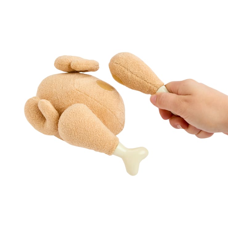 Eine Hand, die einen Plüschtrommelstock hält, neben einem Plüschtier in Form eines gebratenen Truthahns, mit abnehmbaren Trommelstöcken.