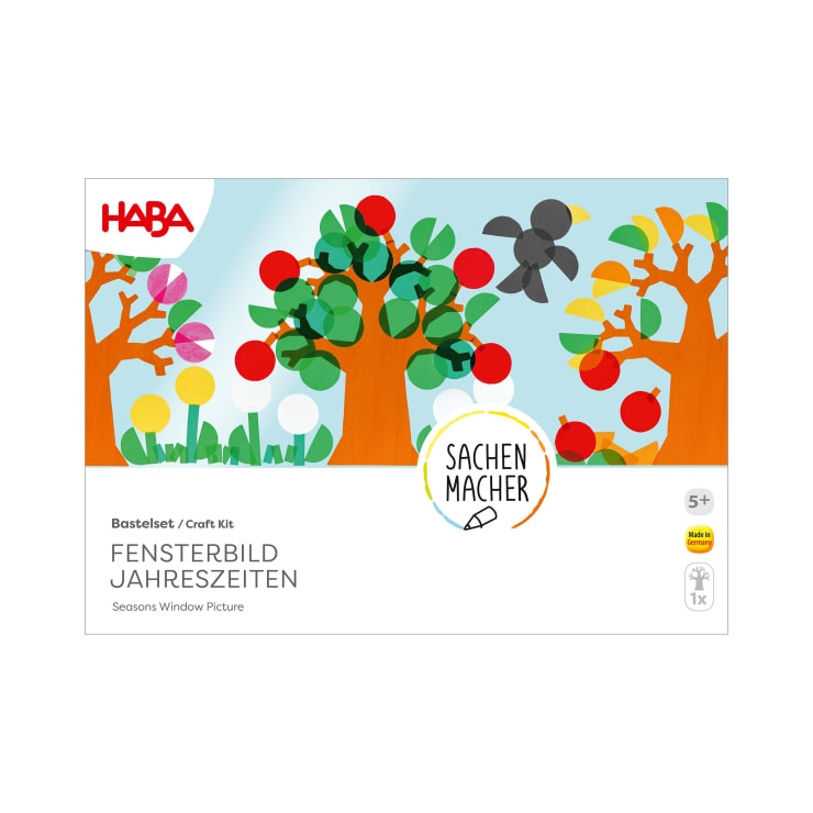 Eine Bastelbox mit der Aufschrift HABA Fensterbild Jahreszeiten zeigt illustrierte Bäume mit bunten Kreisen und einem grauen Vogel. Der Text enthält Sachenmacher und gibt an, dass es für Kinder ab 5 Jahren ist.