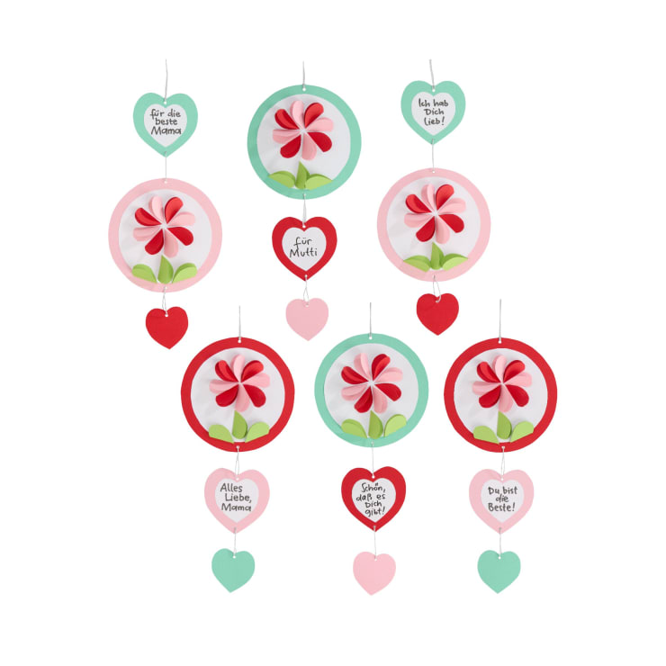 Eine Hängedekoration mit kreisförmigen Blumenmotiven und herzförmigen Anhängern. Die Anhänger tragen deutsche Botschaften wie "Für die beste Mama", "Für Mutti" und "Alles Liebe, Mama". Die Farben sind rosa, rot, grün und weiß.