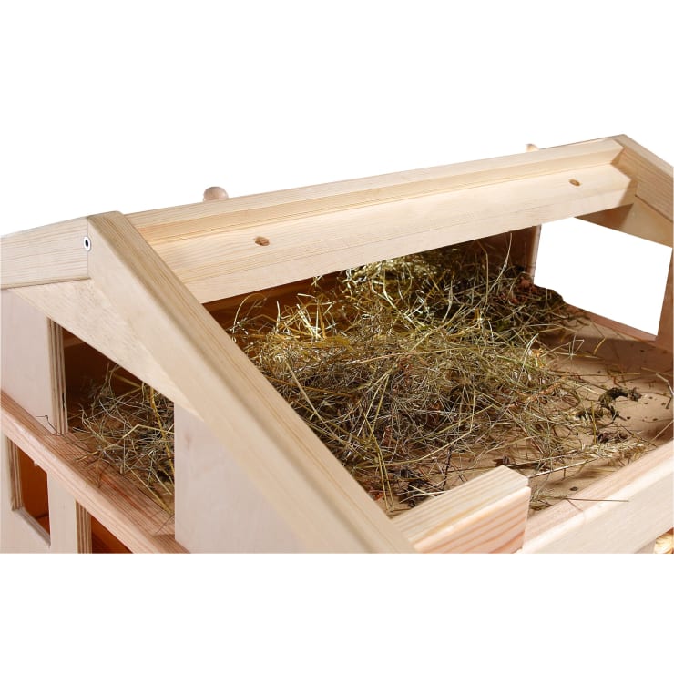Eine Nahaufnahme eines mit trockenem Heu gefüllten Holzstalls. Der Stall ist oben offen und gibt den Blick auf die Stroheinstreu im Inneren frei. Das Holz hat eine helle Farbe und die Struktur wirkt neu und sauber.