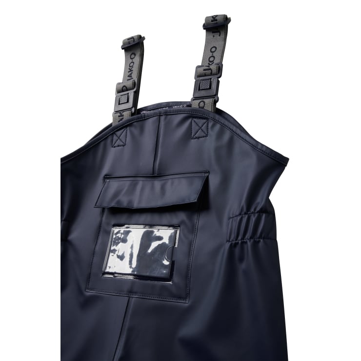 Nahaufnahme des Oberteils eines dunkelblauen wasserdichten Overalls mit verstellbaren grauen Hosenträgern und einer transparenten Tasche auf der Brust.