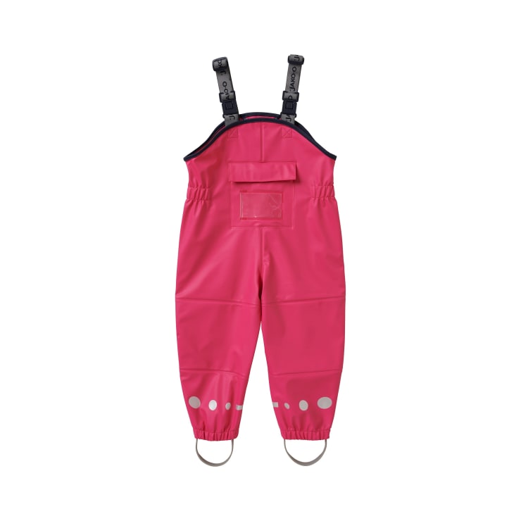 Leuchtend rosafarbener, wasserdichter Kinder-Overall mit Schulterriemen, einer Vordertasche, elastischen Bündchen, reflektierenden Punkten in der Nähe der Knöchel und Fußriemen, flach auf weißem Hintergrund.