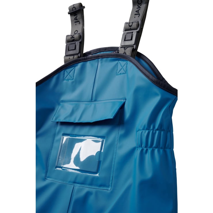 Nahaufnahme eines blauen wasserdichten Overalls mit verstellbaren schwarzen Trägern, einer Vordertasche mit Klappe und einem durchsichtigen Kunststofffenster auf der Tasche. Das Material erscheint glatt und leicht glänzend.