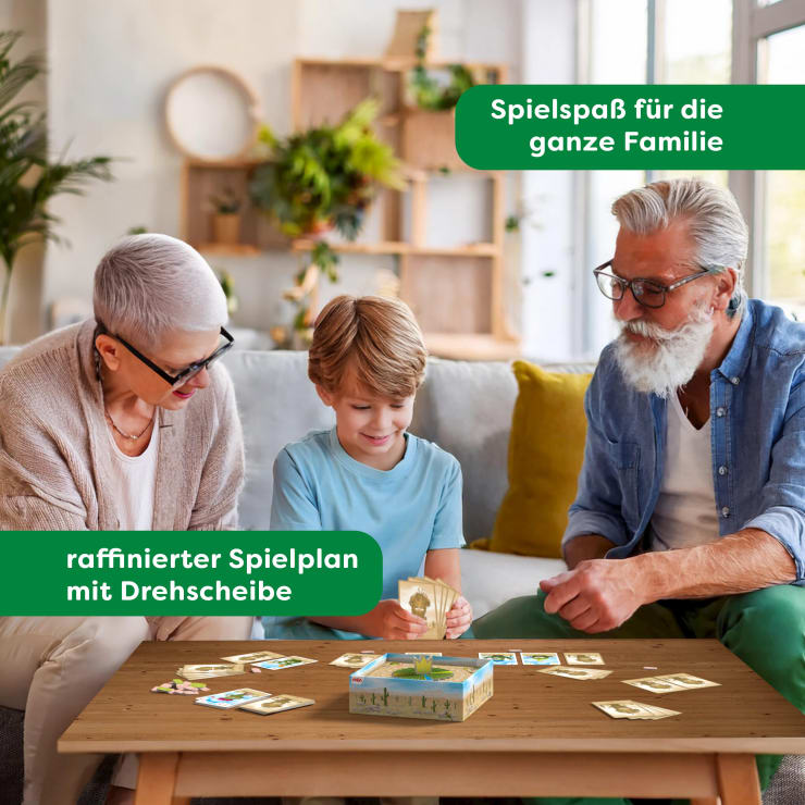 Eine ältere Frau, ein kleiner Junge und ein älterer Mann sitzen an einem Kaffeetisch und spielen gemeinsam ein Karten- und Brettspiel. Der Text auf dem Bild lautet: "Spielspaß für die ganze Familie und raffinierter Spielplan mit Drehscheibe".
