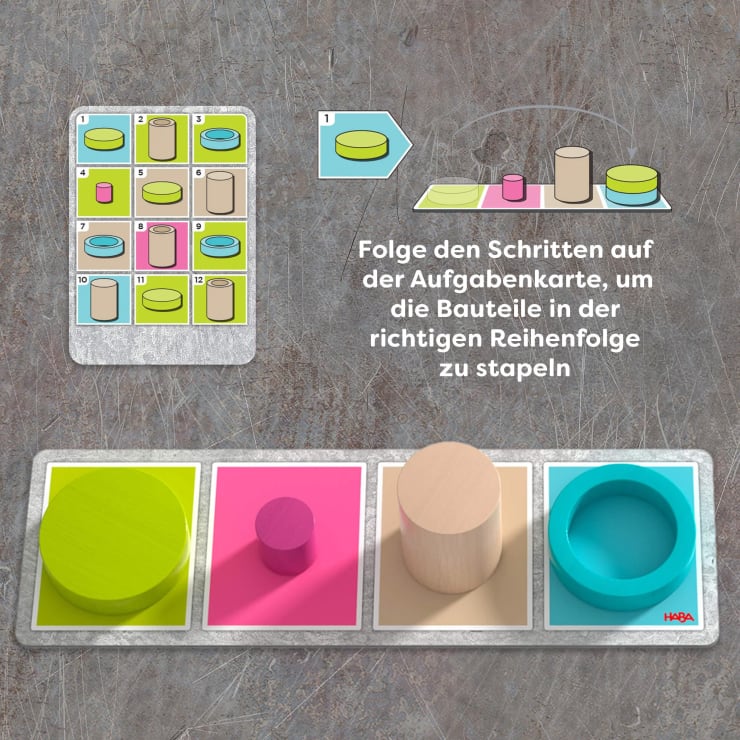 Eine Spielanleitungskarte zeigt, wie man vier farbige Formen - grüner Zylinder, rosa Rechteck, beiger Zylinder und blauer Ring - auf farblich passende Felder stapelt, wobei Pfeile die richtige Reihenfolge anzeigen. Ein Text in deutscher Sprache gibt Anweisungen.