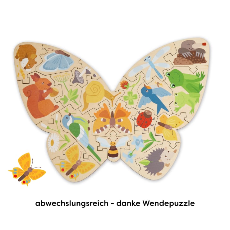 Ein schmetterlingsförmiges Holzpuzzle mit bunten Illustrationen von Tieren und Insekten, darunter ein Eichhörnchen, ein Igel, Frösche, Vögel, Marienkäfer, Schnecken und Schmetterlinge. Der Text darunter lautet: "Abwechslungsreich - danke Wendepuzzle".