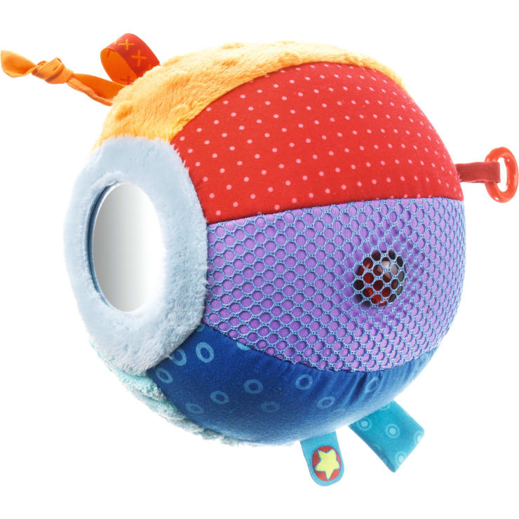 Ein Plüschsensorik-Ball mit verschiedenfarbigen und strukturierten Stoffteilen, einem runden Spiegel, einem Netzbereich, Stoffanhängern und einer Schlaufe, entwickelt für Babys und Kleinkinder.