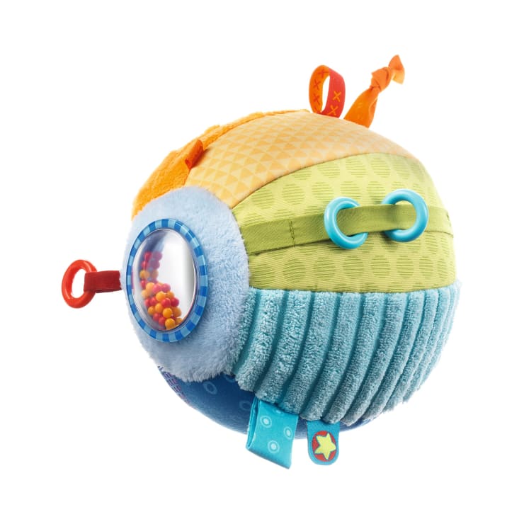 Ein farbenfrohes, rundes Plüsch-Babyspielzeug mit verschiedenen Texturen, Mustern und Stoffanhängern. Es hat ein durchsichtiges Kunststofffenster mit kleinen Perlen darin und mehrere Kunststoffringe an der Oberfläche.