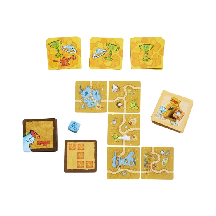 Ein Brettspiel mit gelben und braunen quadratischen Spielsteinen, auf denen Wege, Fußabdrücke und Trophäen abgebildet sind, sowie einem Würfel, der einen blauen Fußabdruck zeigt, und einem Spielstein mit einer offenen Schachtel mit der Aufschrift HABA.