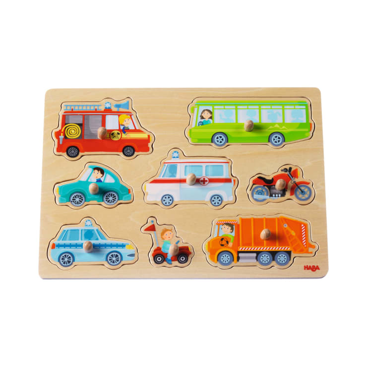 Ein Holzpuzzle mit Teilen, die wie verschiedene Fahrzeuge geformt sind, darunter ein Feuerwehrauto, ein Bus, ein Polizeiauto, ein Krankenwagen, ein Motorrad, ein Müllwagen und ein Kleinwagen, jeweils mit einem Knopf zur einfachen Handhabung.