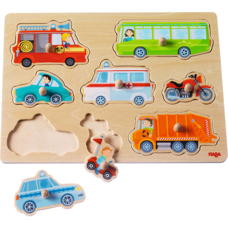 Ein Holzpuzzle mit Cartoon-Notfall- und Servicefahrzeugen, darunter ein Polizeiauto, ein Taxi, ein Feuerwehrauto, ein Krankenwagen, ein Bus, ein Motorrad und ein Kipplaster. Ein Teil ist entfernt und zeigt den leeren Schlitz.